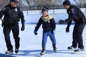 Photo of two Louisville police officers ice skating with a child