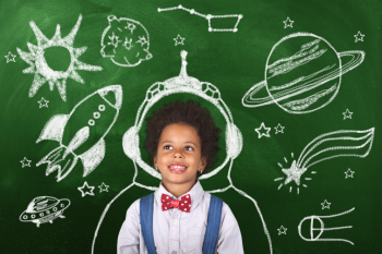 child standing by chalkboard with creative and imaginive doodles