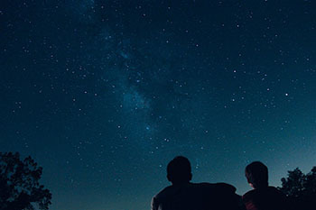 couple stargazing under starry night sky