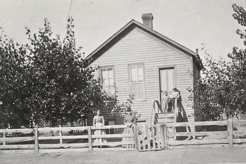 black and white image of a house with a white picket fence.