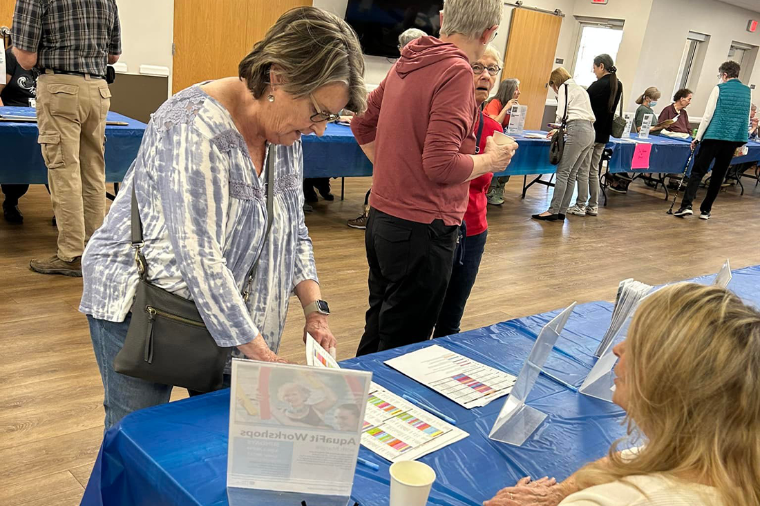 A lady looking at a booth from the Senior Services Showcase