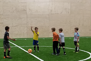 kids playing soccer in the turf gym