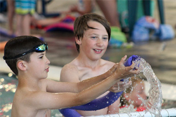 two kids in the pool playing with water