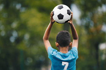 little kid throwing in a soccer ball from the sideline