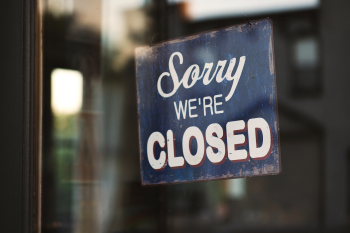 Image of a sign in a door that reads "Sorry, we are closed"