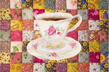 Image of a teacup in front of a quilt.