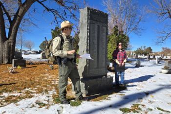 Photo of a park ranger and museum associate next to the WWI memorial at Louisville Cemetery