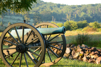 A vintage cannon positioned on a grassy field under a clear blue sky.