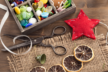 A wooden table displaying a box of buttons, scissors, and various crafting items arranged neatly.