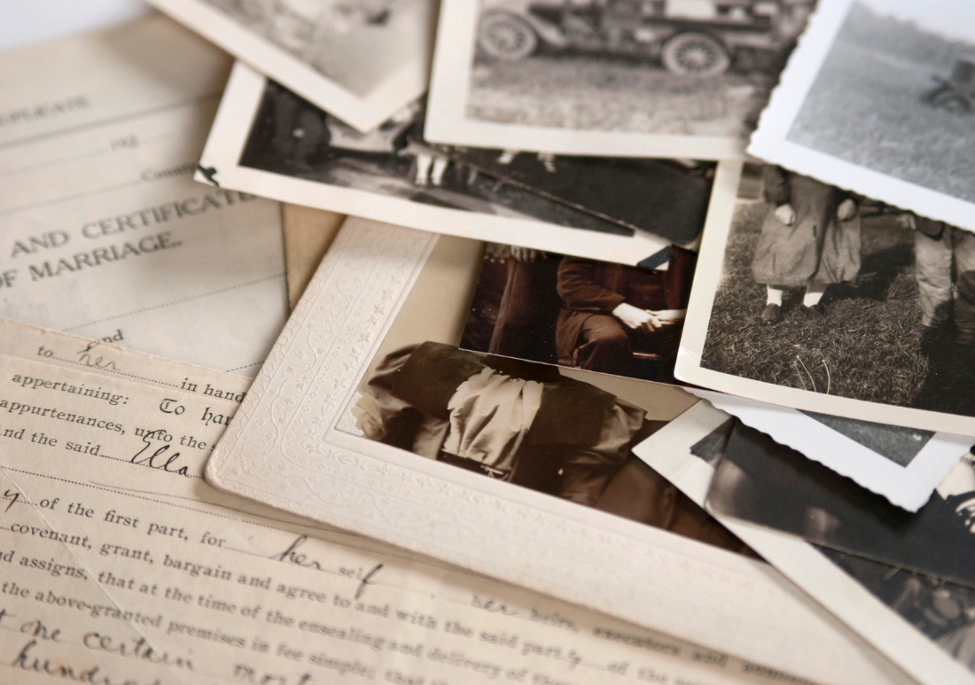 Old photographs and letters scattered across a wooden table, evoking a sense of nostalgia and history.