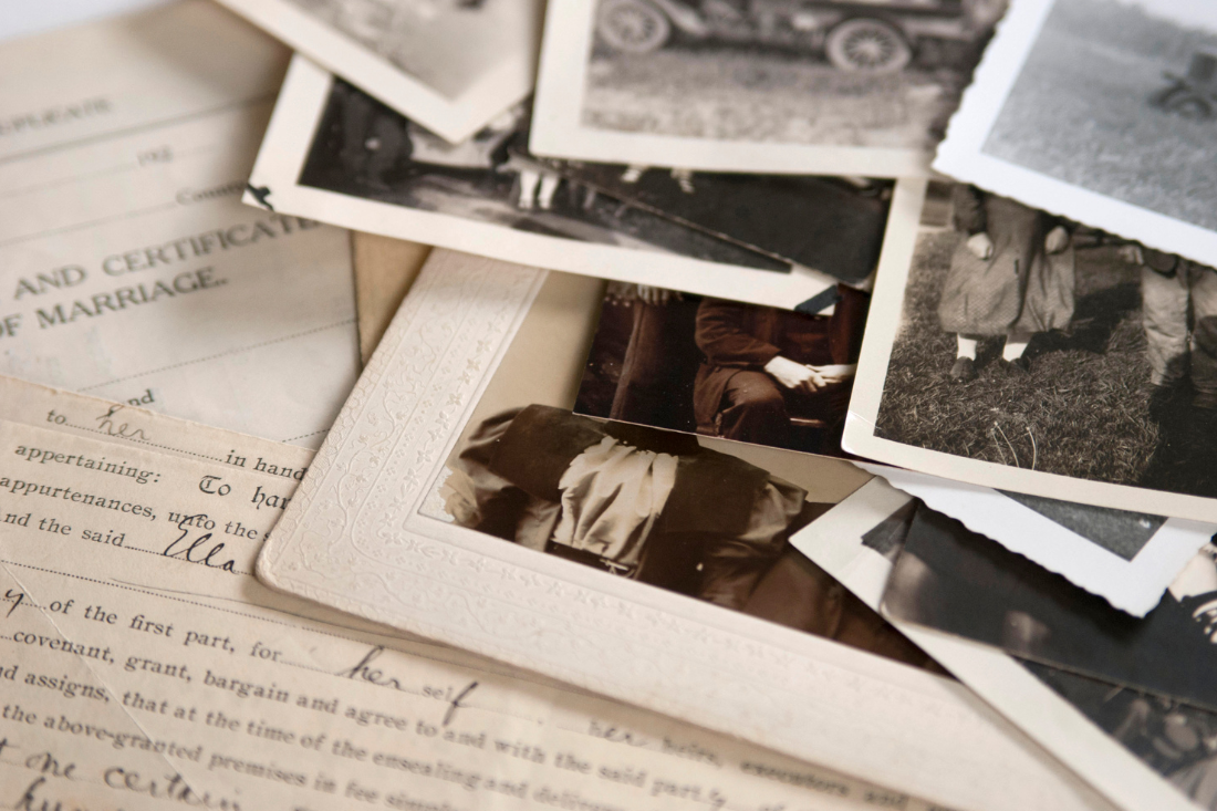 Old photographs and letters scattered across a wooden table, evoking a sense of nostalgia and history