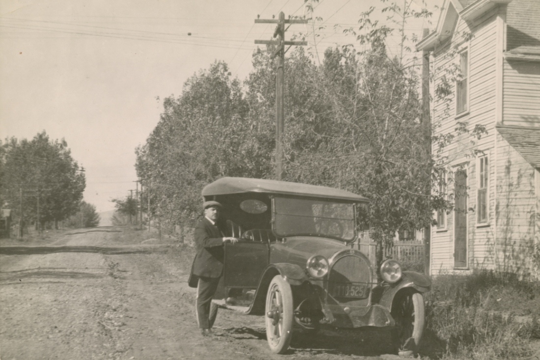 Marcello "Frank" Jacoe poses next to a car on Short St., circa 1910s-1920s.