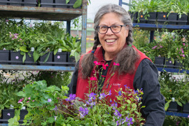 Older woman holding a box of plants from the Resource Central Garden in a Box program