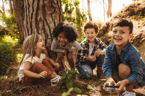 group of young kids in the forest laughing and playing sense of adventure