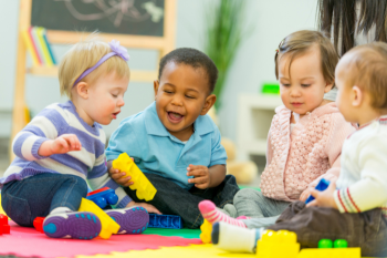 three 12-18 month old infants playing with toys in a group