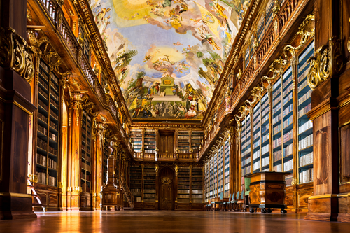 library hall with towering wooden shelves, gilded columns, blue panels, polished floors, and a vivid ceiling fresco.