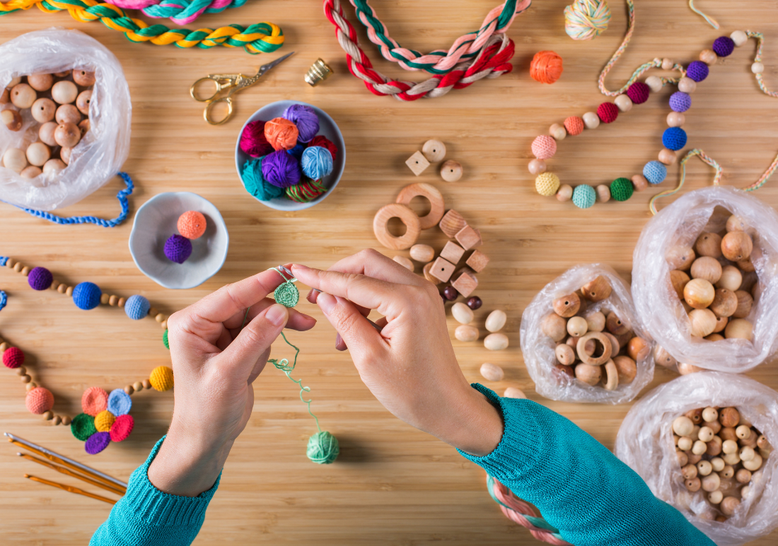 close up of hands crafting with string and beads