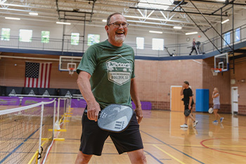 man holding a pickleball paddle and smiling