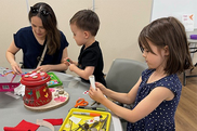 Little girl decorating a fairy house with her mom and brother
