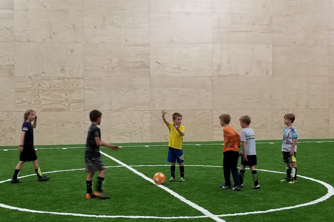 Kids playing soccer in the turf gym