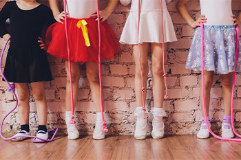 Young kids in a ballet studio standing against the wall 