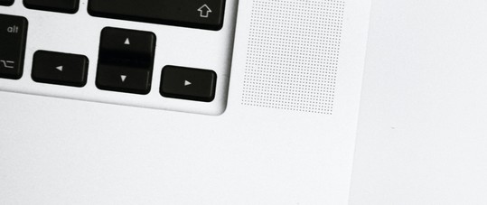 Bottom corner of laptop on a white table.