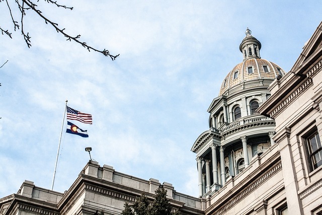 Photo of the upper floors and dome of, and flags flying on, the Colorado State Capitol