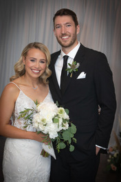 Wedding photo - blonde woman with curled hair in a wedding dress and tall man in tuxedo with brown hair smiling