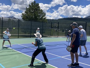 men and women playing pickleball outside
