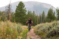 women mountain biking on trail in front of buffalo mountain
