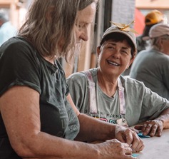 Artist Jennifer Pedersen creating paper cranes with woman