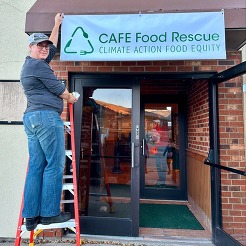 woman hanging sign over door at cafe food rescue 
