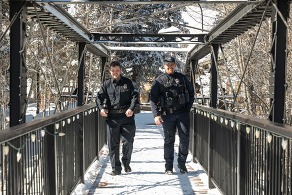 two silverthorne police officers walking across snowy bridge