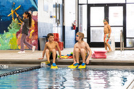 two boys sitting on edge of pool