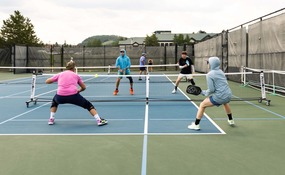 group of adults playing pickleball