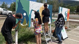 high schoolers painting mural board outside the Art Spot