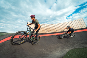 two adults biking on the pump tracks at trent park