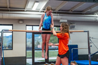 girl on gymnastics bars with coach