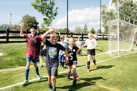 Kids smiling and running on the soccer field