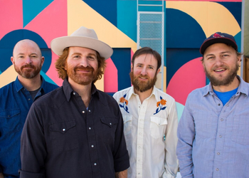 Four smiling Chain Station band members standing 