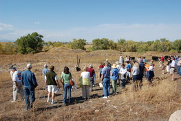 People walking a trail in a field listening to history of the area