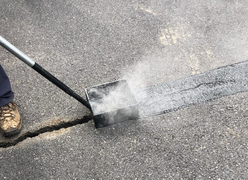 Steam comes off as asphalt placed on cracks in the pavement