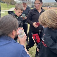 Man holding a bee in a cup showing it to the children volunteers