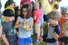 Child holding a snake while surrounded by other children