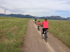 People riding their bikes in the Boulder Open Space with the mountains in the background 