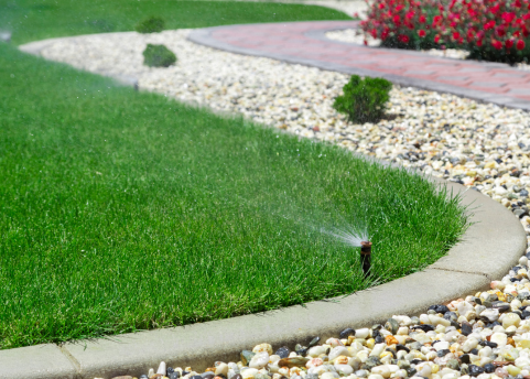 Sprinker watering grass with stone border