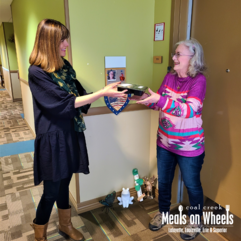 Woman from coal creek meals on wheels handing over a meal