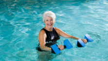 Water aerobics instructor in the pool with hand weights