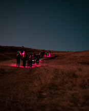 A dim red light barley lighting the environment as hikers take the coyote ridge trail