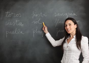 Woman points to Spanish words on a chalkboard
